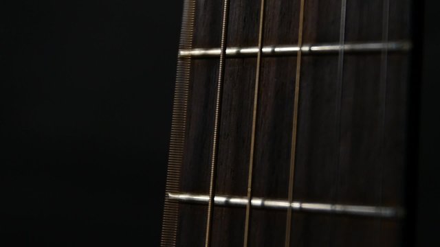 Acoustic guitar strings, close up, slow motion, on black