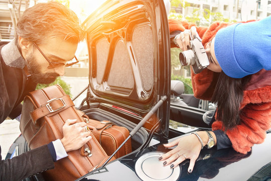 Hipster fashion couple having fun at loading leather suitcase