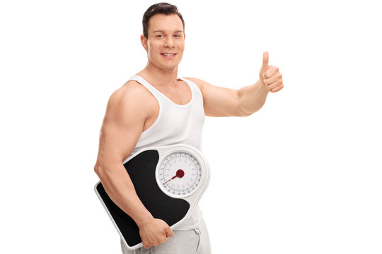 Guy holding a weight scale and giving thumb up