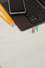 School or student supplies with closed slim notebook and smartphone on a white wooden table surface