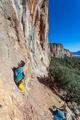 Fototapeta premium Mature male extreme Climber moving up on belay of partner