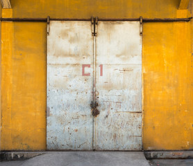 Locked metal grunge metal door on yellow wall