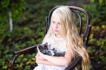 Baby girl holding hands a kitten in the light of sunset, pet, friend,