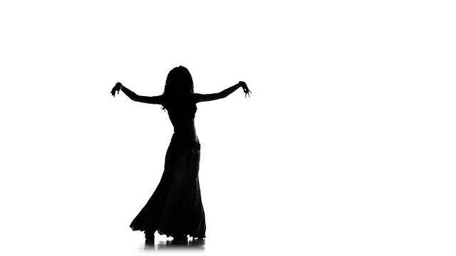 Beautiful young exotic belly dancer shaking her hips, on white, slow motion, silhouette