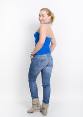 beautiful young leggy blond girl in a jeans and a blue shirt  in a boots, full height posing