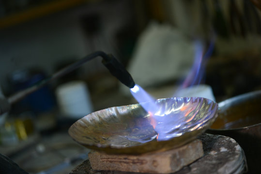 Master goldsmith working with silver-Annealing the metal to make