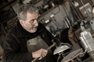 Obraz na płótnie Canvas Master goldsmith working with silver-Shaping of the object by ha