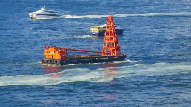 Industrial crane boat nautical vessel floating to ship dock in Hong Kong harbor