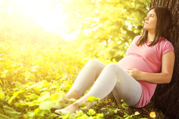 Naklejka na ściany i meble Pregnant woman sitting on grass