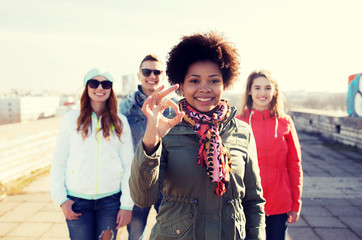 happy teenage friends showing ok sign on street