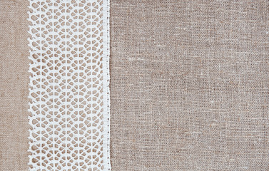Fototapeta premium Vintage background with lace fabric on burlap cloth