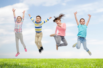 happy children jumping in air over sky and grass