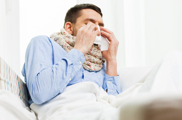 ill man blowing nose with paper napkin at home
