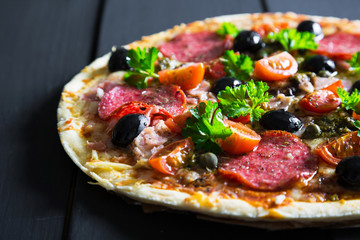Pizza with salami, olives and herbs