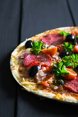 Pizza with salami, olives and herbs