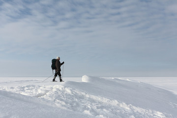 Fototapeta na wymiar The man the traveler with a backpack skiing on snow of the froze