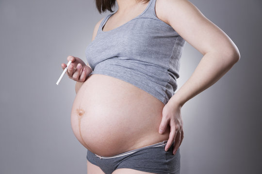 Pregnant woman quits smoking. Studio shot on a gray background