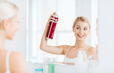 woman with hairspray styling her hair at bathroom