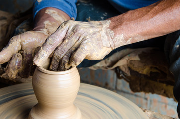 Hands of making clay pot on the pottery wheel ,select focus, close-up.