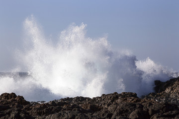 Fototapeta na wymiar water splash or spray by breaking waves on rocky shore of punta