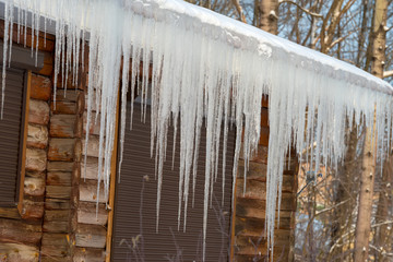 Large icicles hanging from a wooden house roof