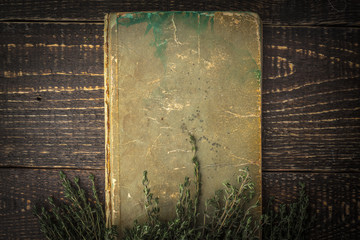 Old book with thyme on the wooden table top view