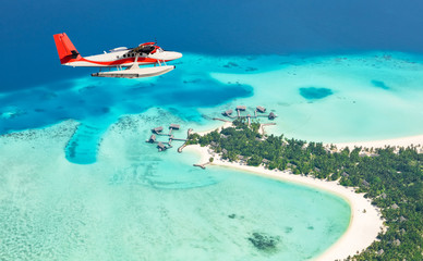 Sea plane flying above Maldives islands - obrazy, fototapety, plakaty
