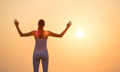 Fototapeta na wymiar Young woman practising yoga in sunset