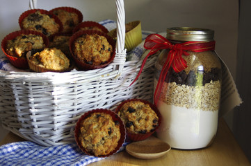 Homemade muffins in a white basket with a jar of ingredients