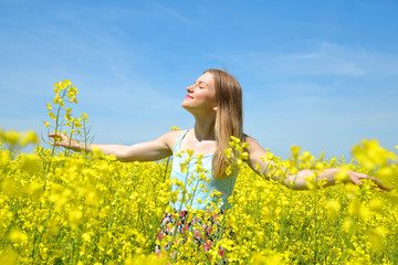 Naklejka na ściany i meble Young happy woman on blooming rapeseed field in spring