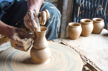 Hands of making clay pot on the pottery wheel ,select focus, close-up.