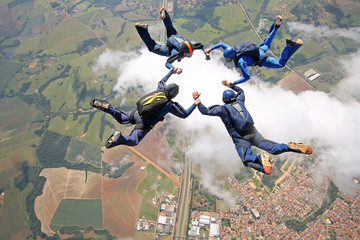 Skydivers make a star formation above the clouds. - 104187748