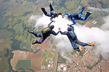 Foto op Canvas Skydivers make a star formation above the clouds. © Mauricio G
