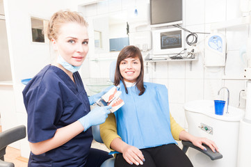 Beautiful female dentist with plastic jaw imitation and toothbru