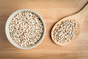 bowl of millet and a scoop of millet on the wood background