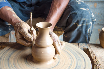 Hands of making clay pot on the pottery wheel ,select focus, close-up.