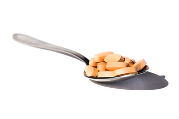 Orange pills in spoon on a white background