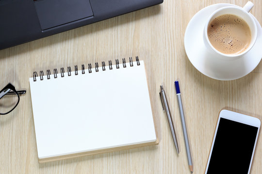 Top view of office desk with notepad, smartphone, glasses, coffe