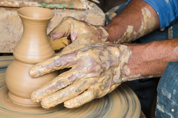 Hands of making clay pot on the pottery wheel ,select focus, close-up.