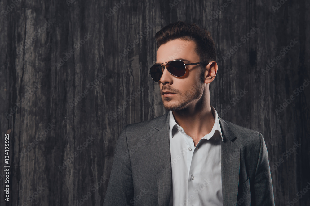 Wall mural Portrait of trendy young man in gray suit and spectacles