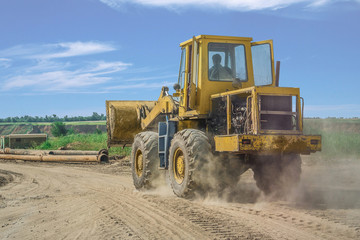 yellow bulldozer rides on the sand road
