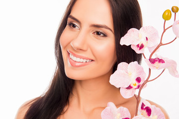Close up photo of smiling brunette holding orchid near her face