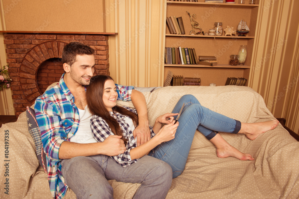 Poster happy cute couple in love serfing net on the sofa