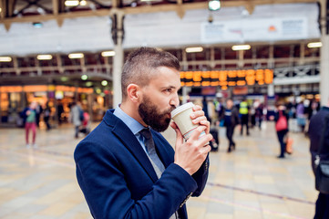 Hipster businessman drinking coffee at the train station