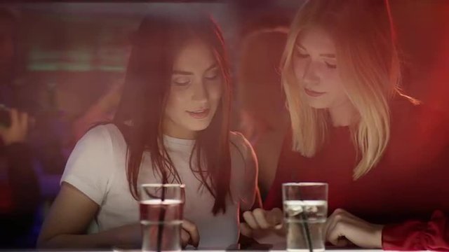 Girls at the bar typing on smartphone