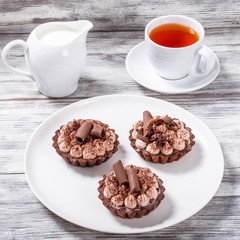 delicious chocolate cupcakes with a cup of tea and a jug of milk