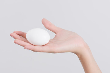 Fototapeta na wymiar Woman hand holding White egg, isolated on white background