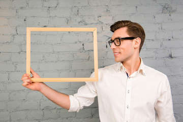 Smiling man in glasses and white shirt  holding wooden frame