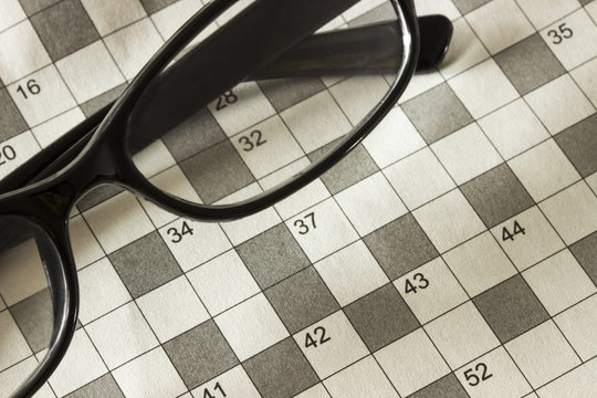 Background of the pages of the magazine with the crossword puzzle and glasses. Close up. Cropped