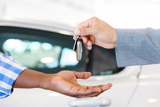 car dealer handing over new car key to customer
